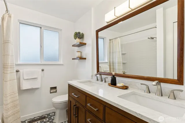 a bathroom with a double vanity sink toilet and mirror