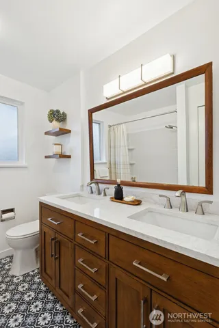 a bathroom with a granite countertop sink mirror and a toilet