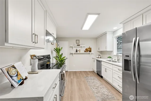 a kitchen with stainless steel appliances granite countertop a refrigerator a stove a sink dishwasher and white cabinets with wooden floor