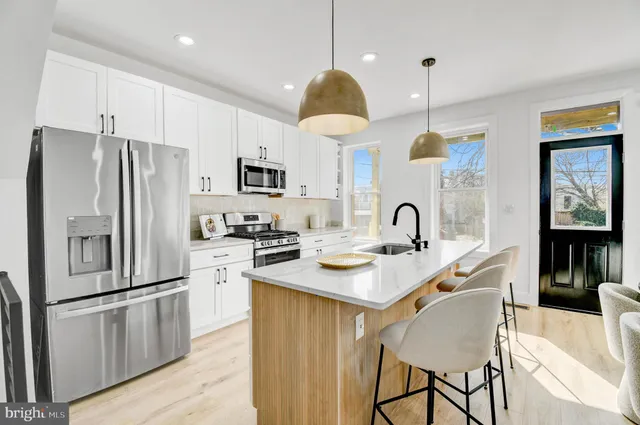 a kitchen with stainless steel appliances granite countertop a refrigerator a sink a stove and white cabinets