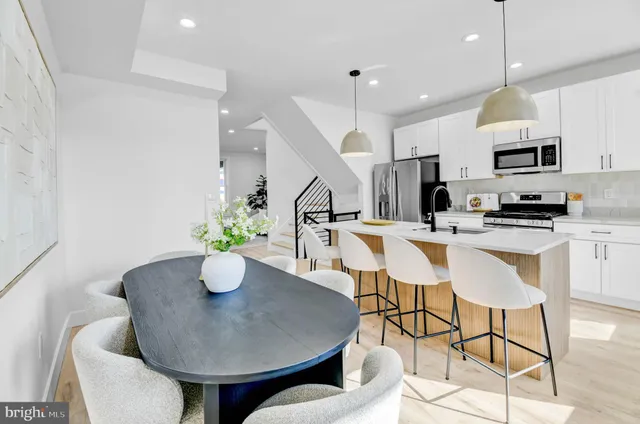 a kitchen with stainless steel appliances kitchen island granite countertop a sink a microwave a dining table and chairs