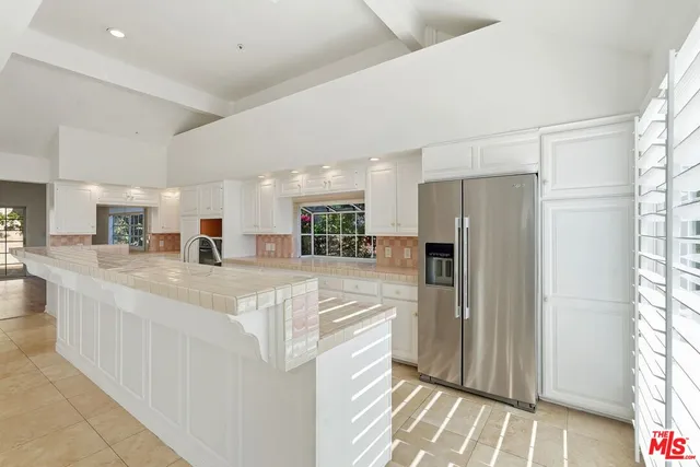 a large white kitchen with a refrigerator a stove and a sink
