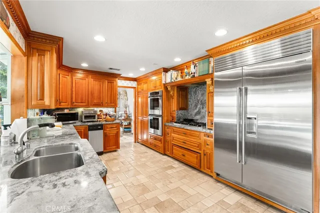 a kitchen with stainless steel appliances granite countertop a sink a stove and a refrigerator
