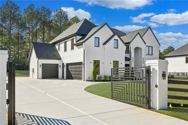 a view of a white house with large trees and playing area in front of it