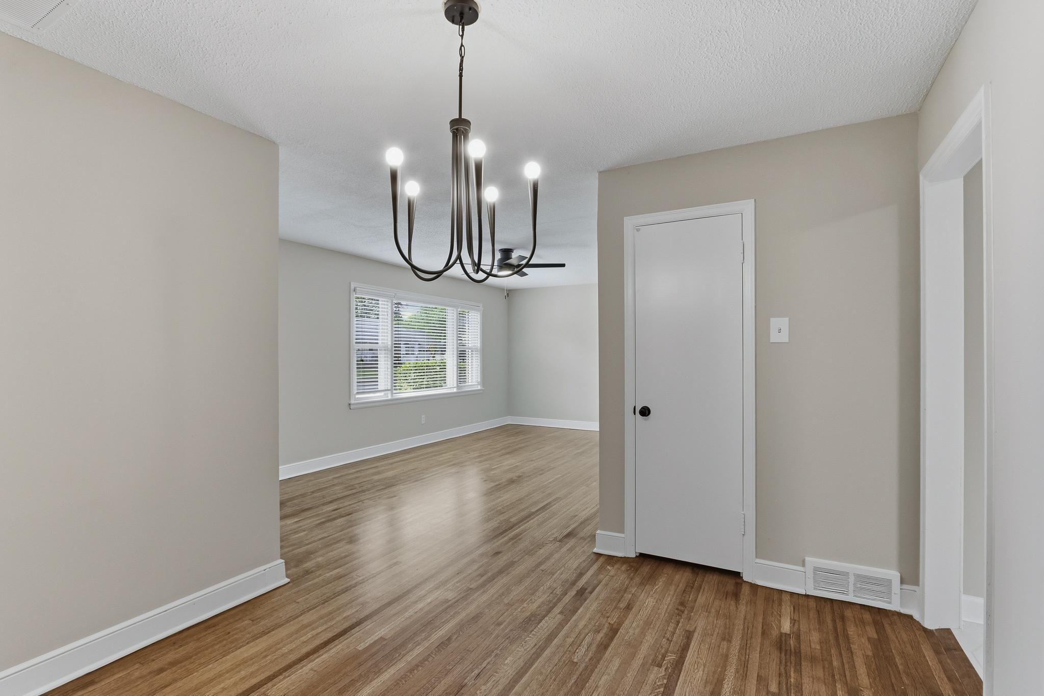 312 Fernway Road Memphis, TN 38117 - Photo 12 of 38 Unfurnished dining area with a chandelier, light wood-style floors, and a textured ceiling
