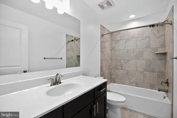 a bathroom with a sink a toilet a mirror a bathtub and shower