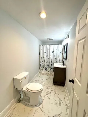 a bathroom with a granite countertop toilet a sink and a mirror