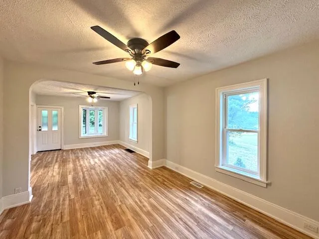 a view of an empty room with window and wooden floor