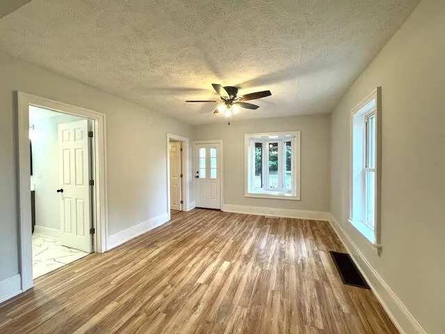 a view of an empty room with a window and wooden floor