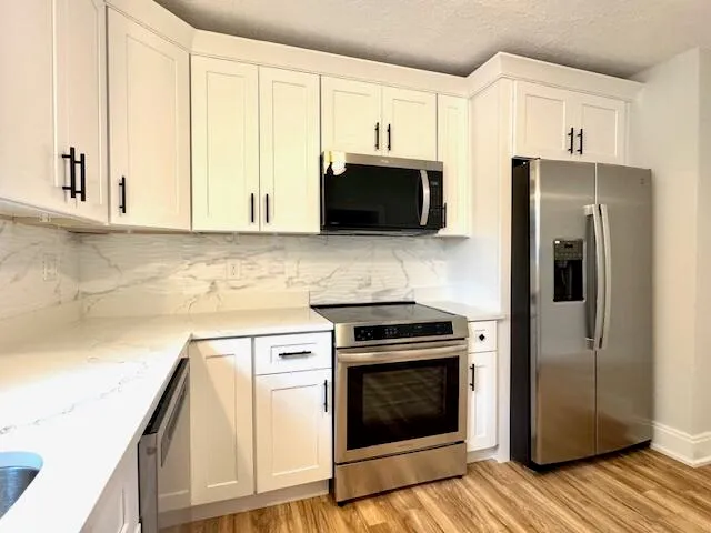 a kitchen with cabinets stainless steel appliances and wooden floor