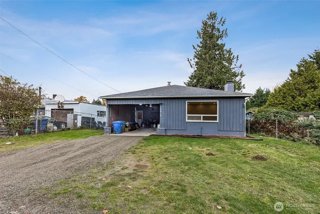 a view of a house with a yard and a large tree