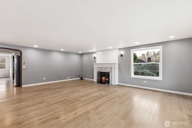 an empty room with windows fireplace and wooden floor