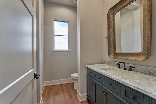 a bathroom with a granite countertop toilet a sink and a mirror