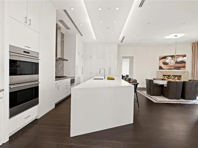 a dining room with wooden floor a chandelier a glass table and chairs