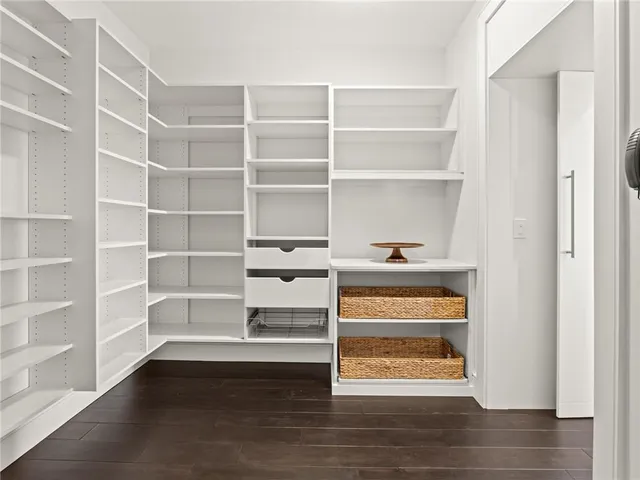 an empty room with wooden floor chandelier and windows