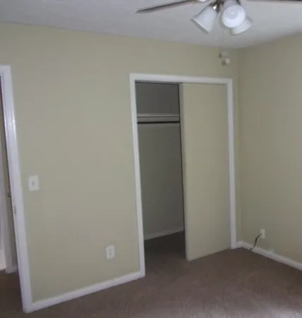 an empty room with closet and a chandelier fan