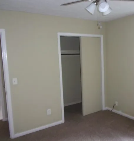 an empty room with closet and a chandelier fan