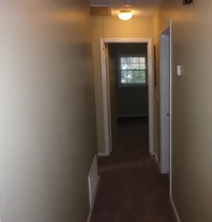 a view of a hallway with wooden floor and a living room