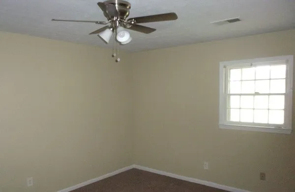 an empty room with a window and a fan