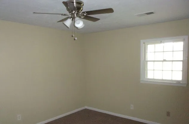 an empty room with a window and a fan