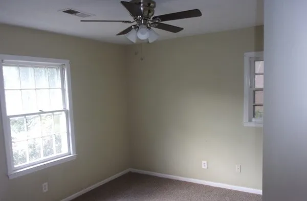an empty room with a window and a fan