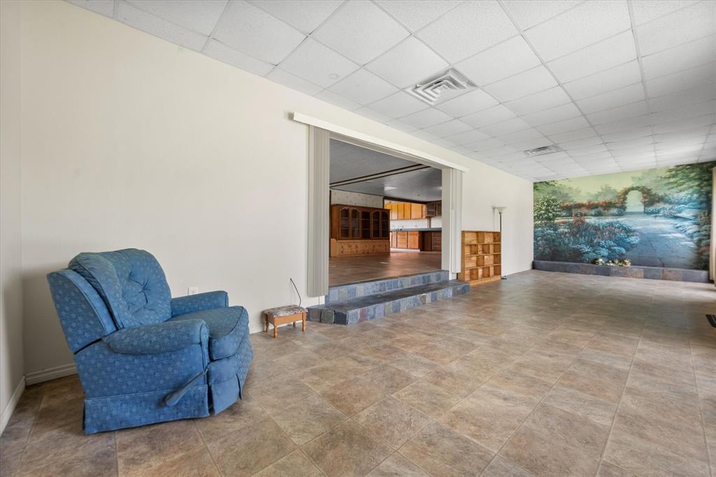 2101 Ridge View Drive Cleburne, TX 76033 - Photo 10 of 31 Spacious room featuring neutral-toned tile flooring, a drop ceiling, and a large wall mural depicting a garden scene