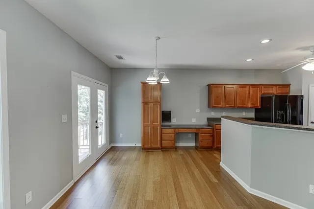 a kitchen with stainless steel appliances granite countertop a refrigerator a sink dishwasher a stove and white countertops with wooden floor