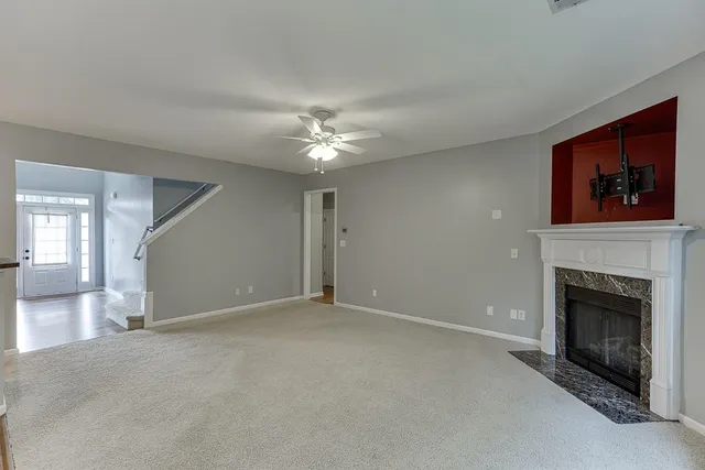 a view of an empty room with chandelier fan and fire place