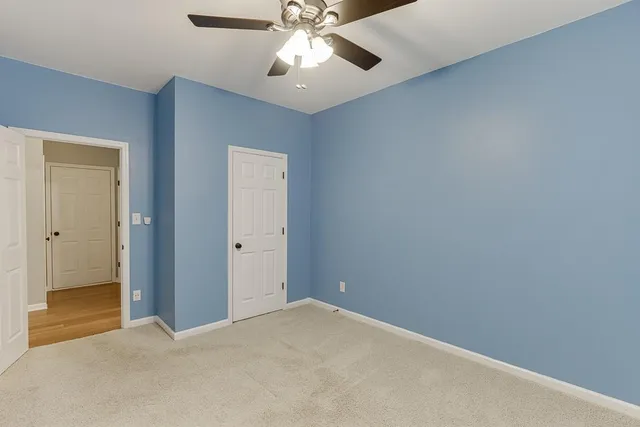 an empty room with closet and a chandelier fan