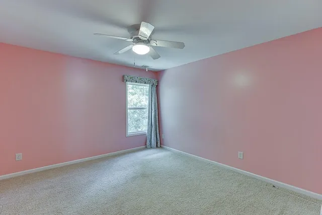 an empty room with a chandelier fan and windows