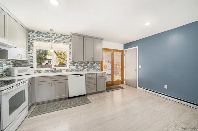a kitchen with granite countertop a stove a sink and a refrigerator