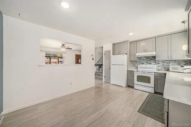 a kitchen with granite countertop white cabinets and white appliances