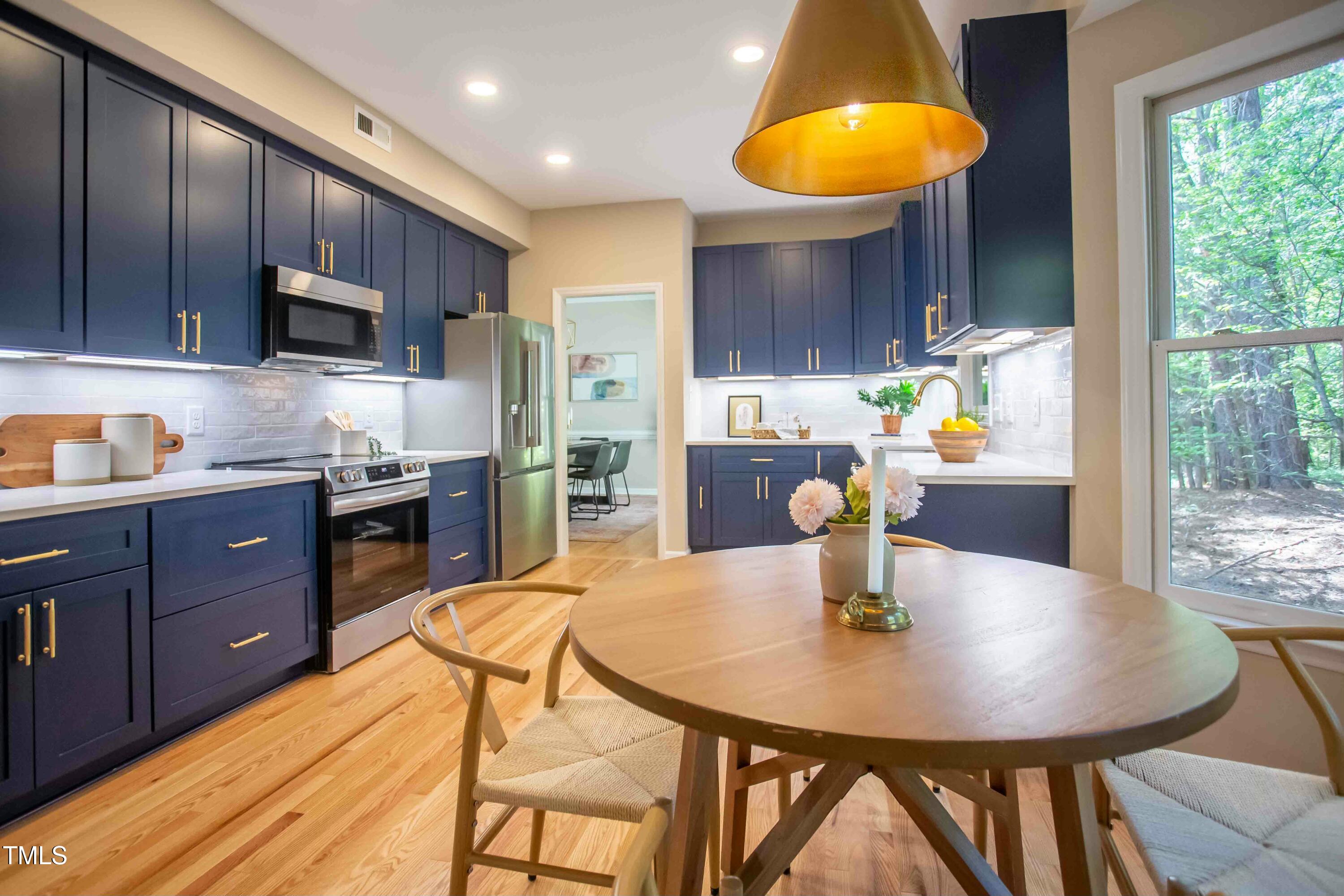 103 Windhover Drive Chapel Hill, NC 27514 - Photo 19 of 61 a kitchen with stainless steel appliances wooden table a stove a kitchen island a dining table and chairs