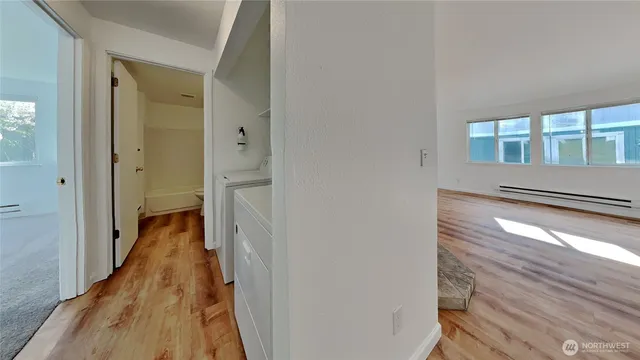 a view of a hallway with wooden floor and a bathroom