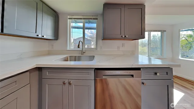 a kitchen with stainless steel appliances granite countertop a sink dishwasher a refrigerator and cabinets with wooden floor