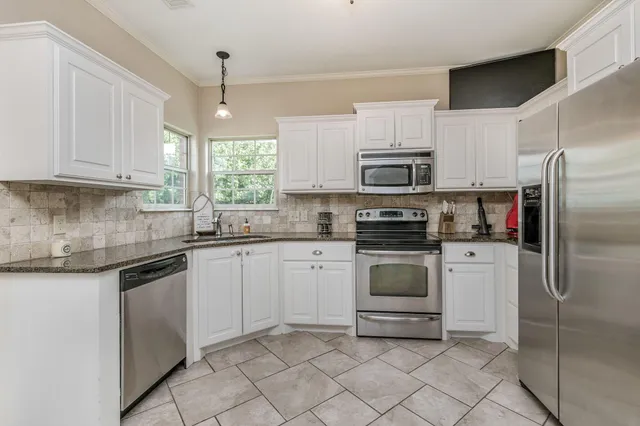 a kitchen with granite countertop white cabinets and stainless steel appliances