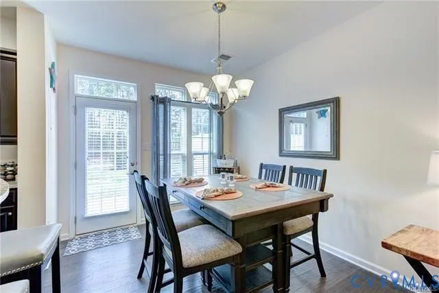 a dining room with wooden floor a chandelier a wooden table and chairs