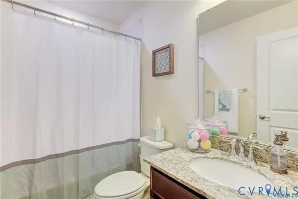 a bathroom with a granite countertop sink mirror vanity and toilet