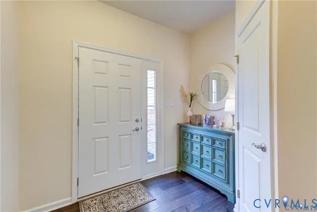 a view of a hallway with front door wooden floor and cabinet