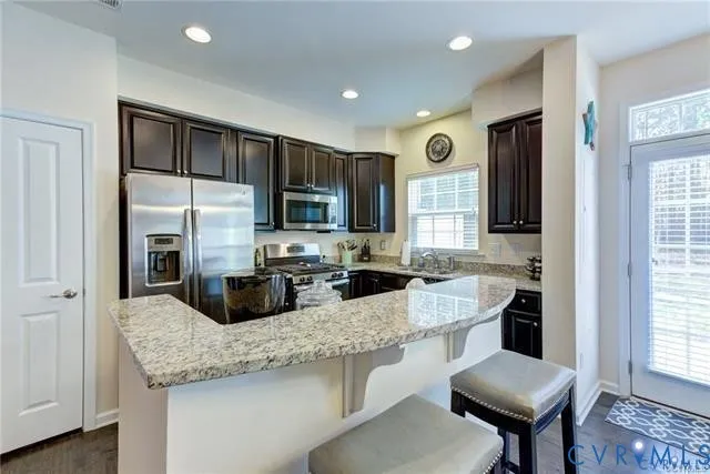 a kitchen with stainless steel appliances granite countertop a sink refrigerator and microwave