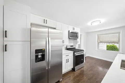 a kitchen with a refrigerator a stove a microwave and a window