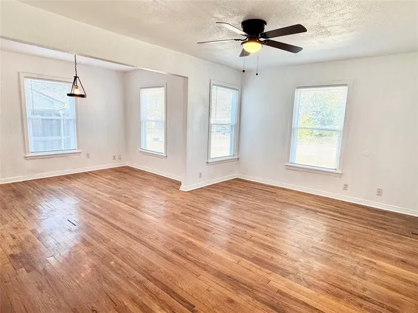 a view of an empty room with window and wooden floor
