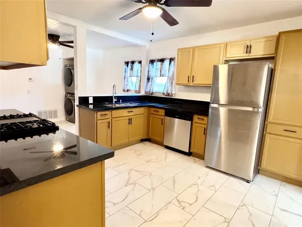 a kitchen with stainless steel appliances granite countertop a refrigerator a sink a stove and white cabinets