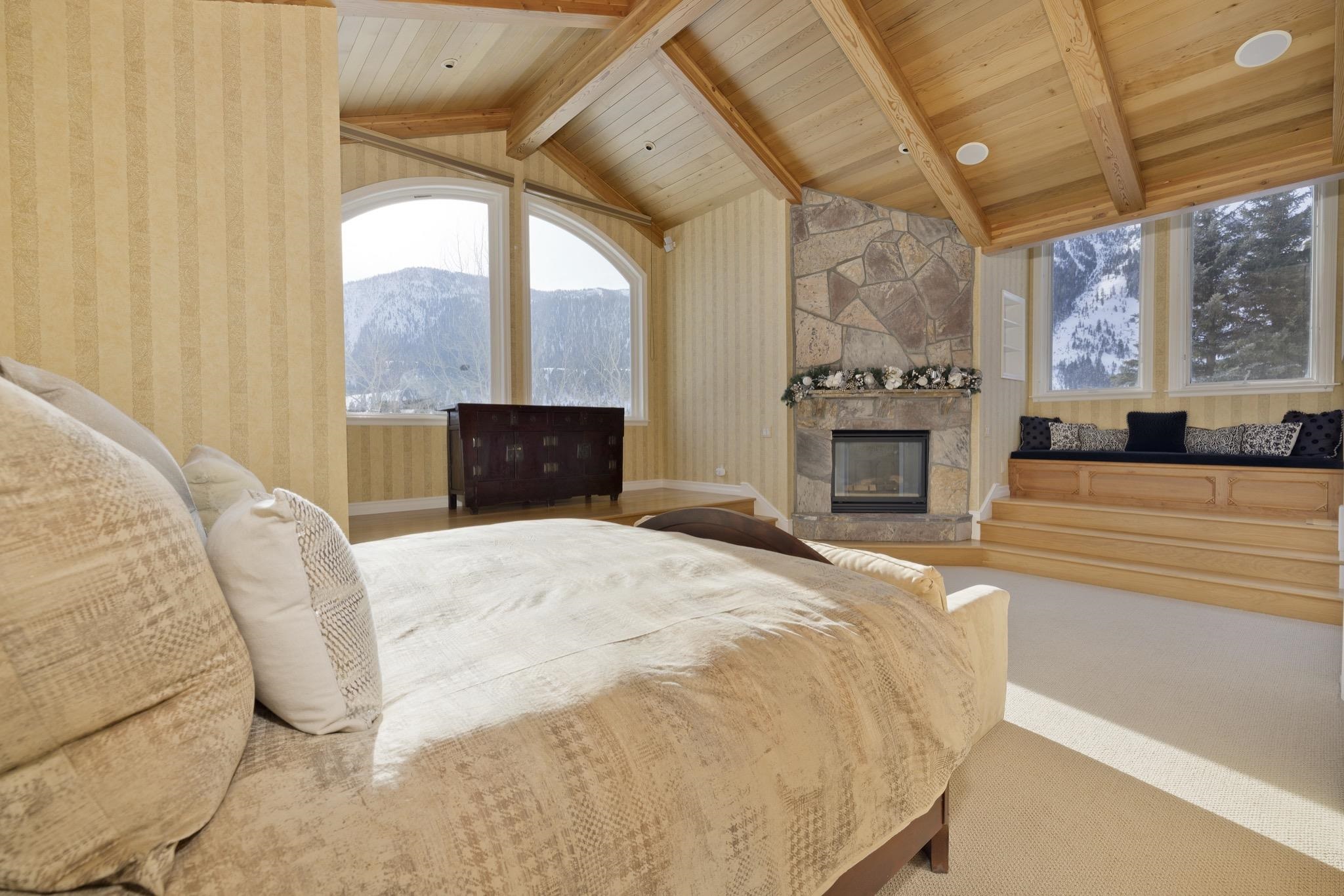 370 Ranch Road Mammoth Lakes, CA 93546 - Photo 25 of 46 Bedroom featuring a stone fireplace, carpet floors, wallpapered walls, wood ceiling, and a mountain view