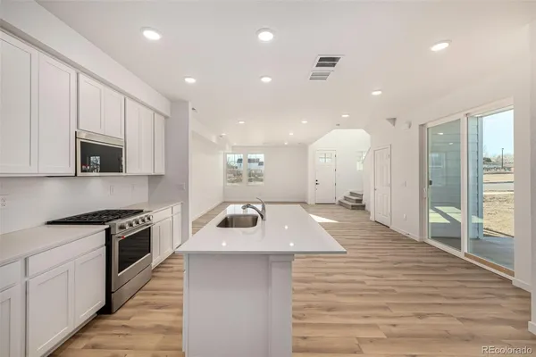 a large kitchen with stainless steel appliances granite countertop a large kitchen island a stove and a wooden floors