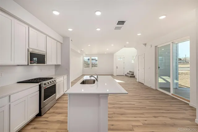 a large kitchen with stainless steel appliances granite countertop a large kitchen island a stove and a wooden floors