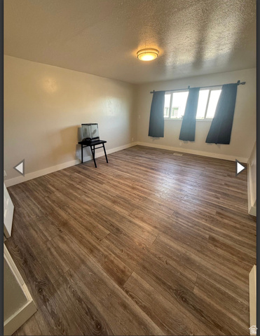 102 East Richelman Lane Wellington, UT 84542 - Photo 22 of 39 Unfurnished room with dark wood-style floors and a textured ceiling