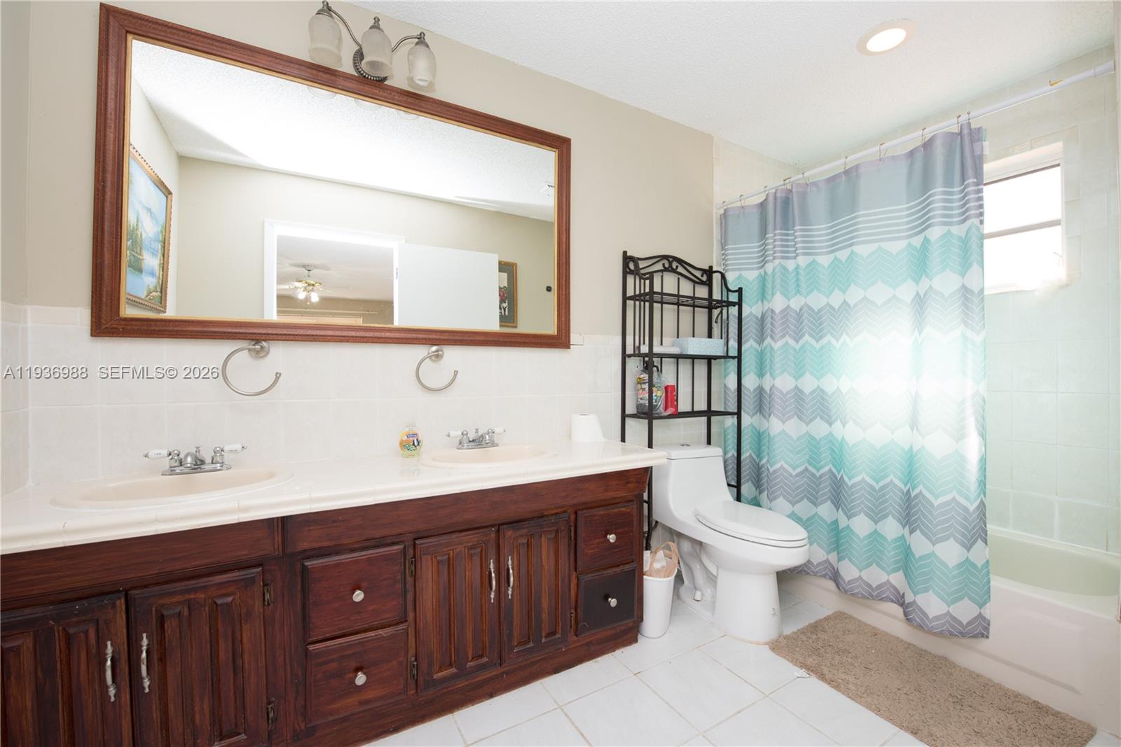 21295 Southwest 376th Street Homestead, FL 33034 - Photo 17 of 51 a bathroom with a double vanity sink toilet mirror and shower