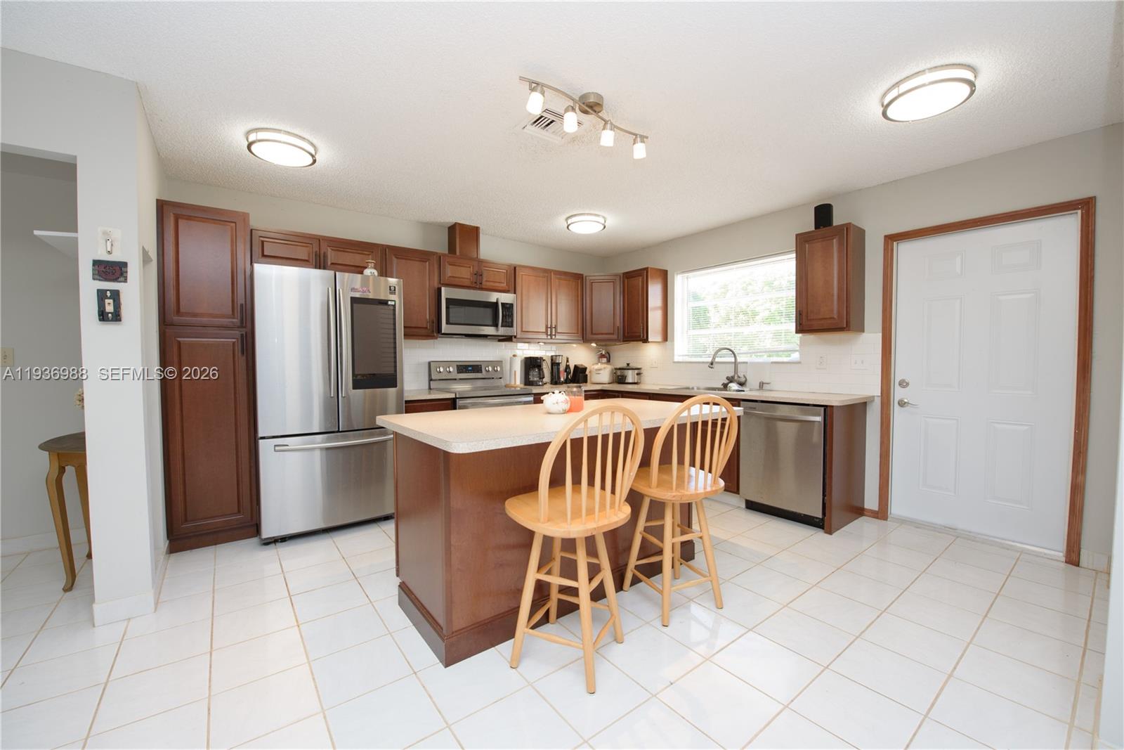 21295 Southwest 376th Street Homestead, FL 33034 - Photo 7 of 51 a kitchen with stainless steel appliances a sink a stove a refrigerator cabinets and a dining table