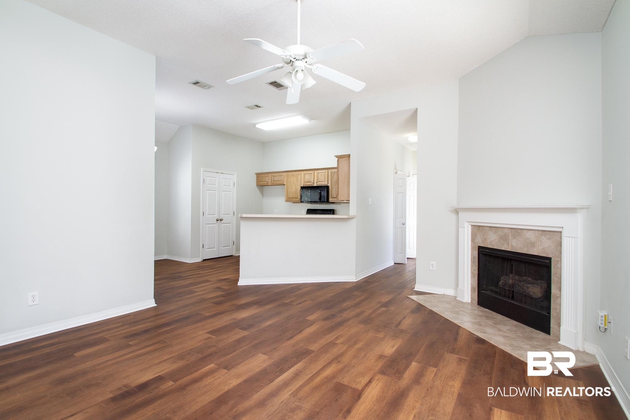 View as you walk in featuring a tiled gas log fireplace, new Luxury Vinyl Plank flooring and ceiling fan!